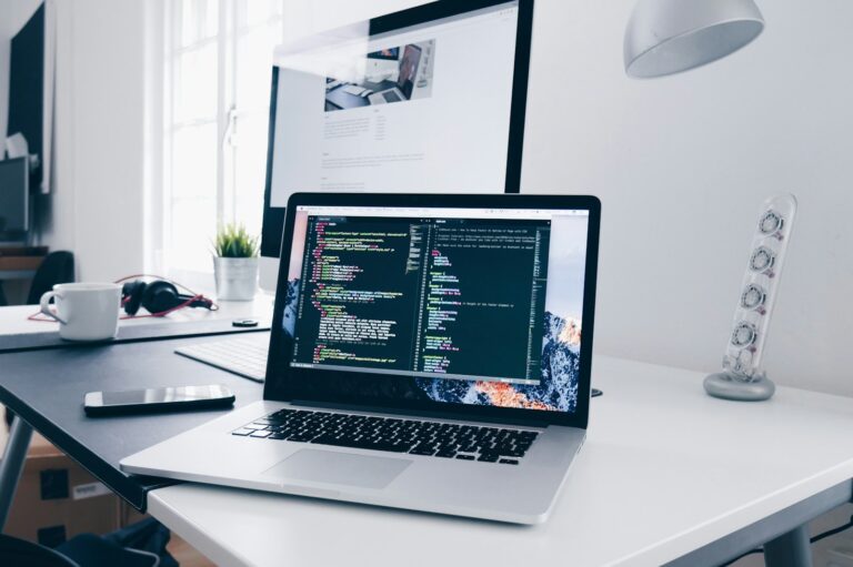 Portátil con código en pantalla sobre una mesa de trabajo